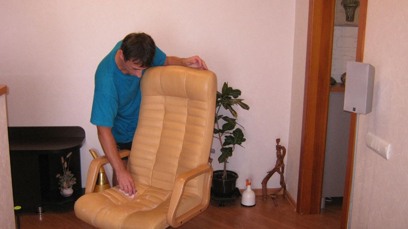 Мастер производит химчистку кожаного кресла